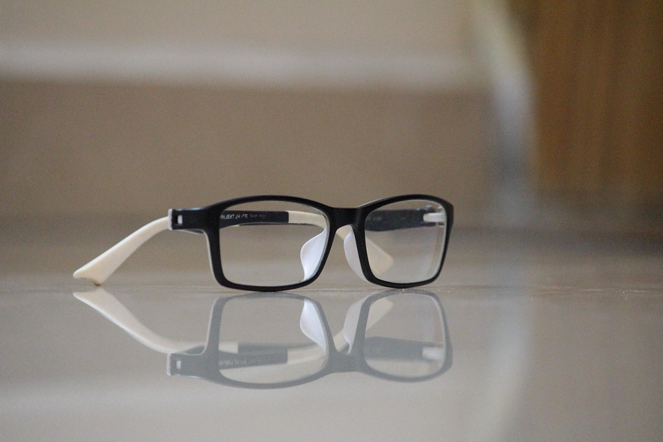 Black-and-white eyewear resting on a reflective surface.