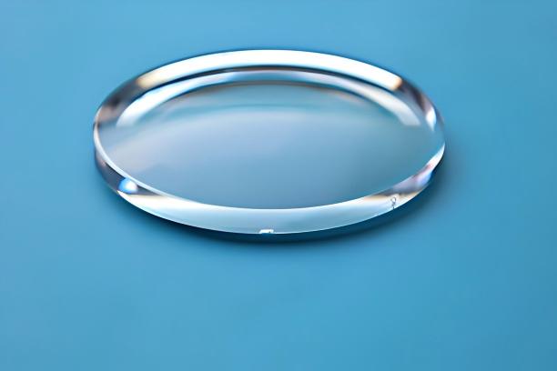 Clear circular optical element resting on a blue surface