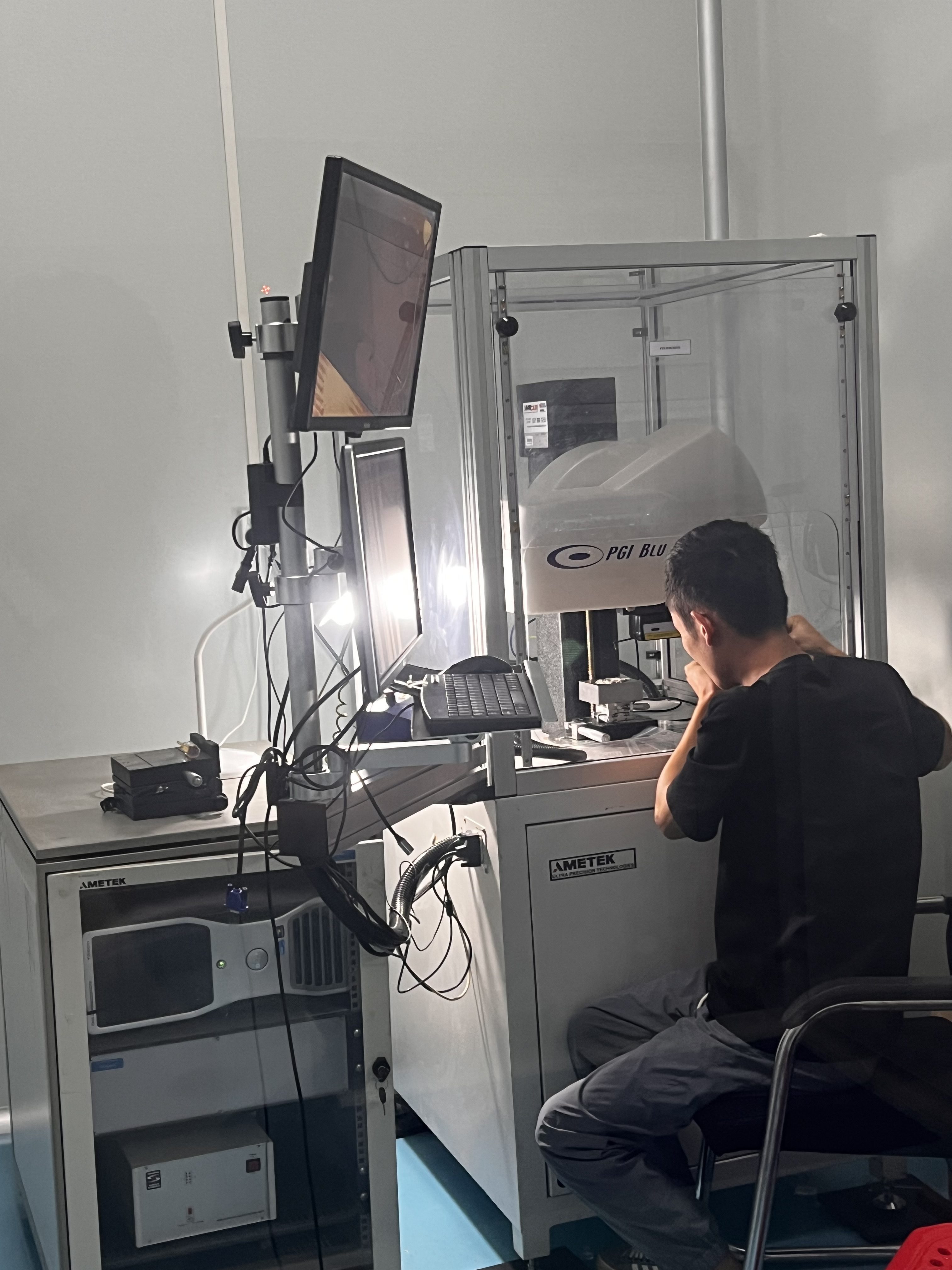 Operator seated at an enclosed inspection station beside two monitors
