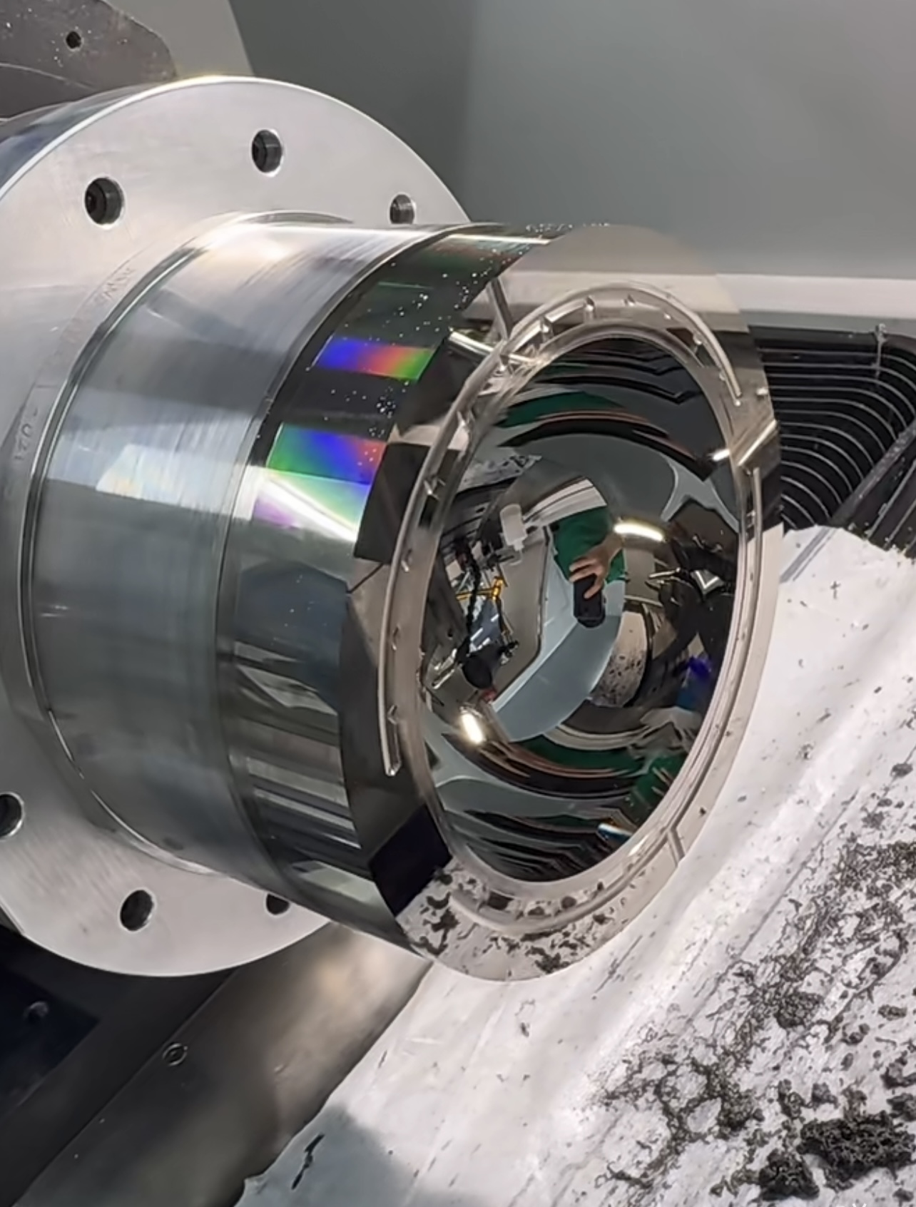 Reflective curved metal workpiece mounted in a machining fixture